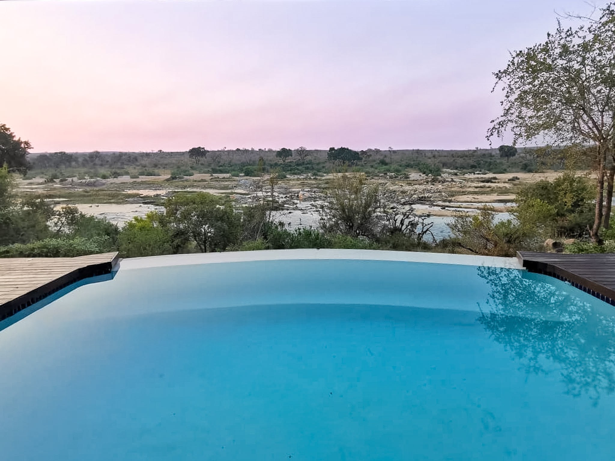 The rim-flow pool at dusk with the Crocodile River and reserve beyond