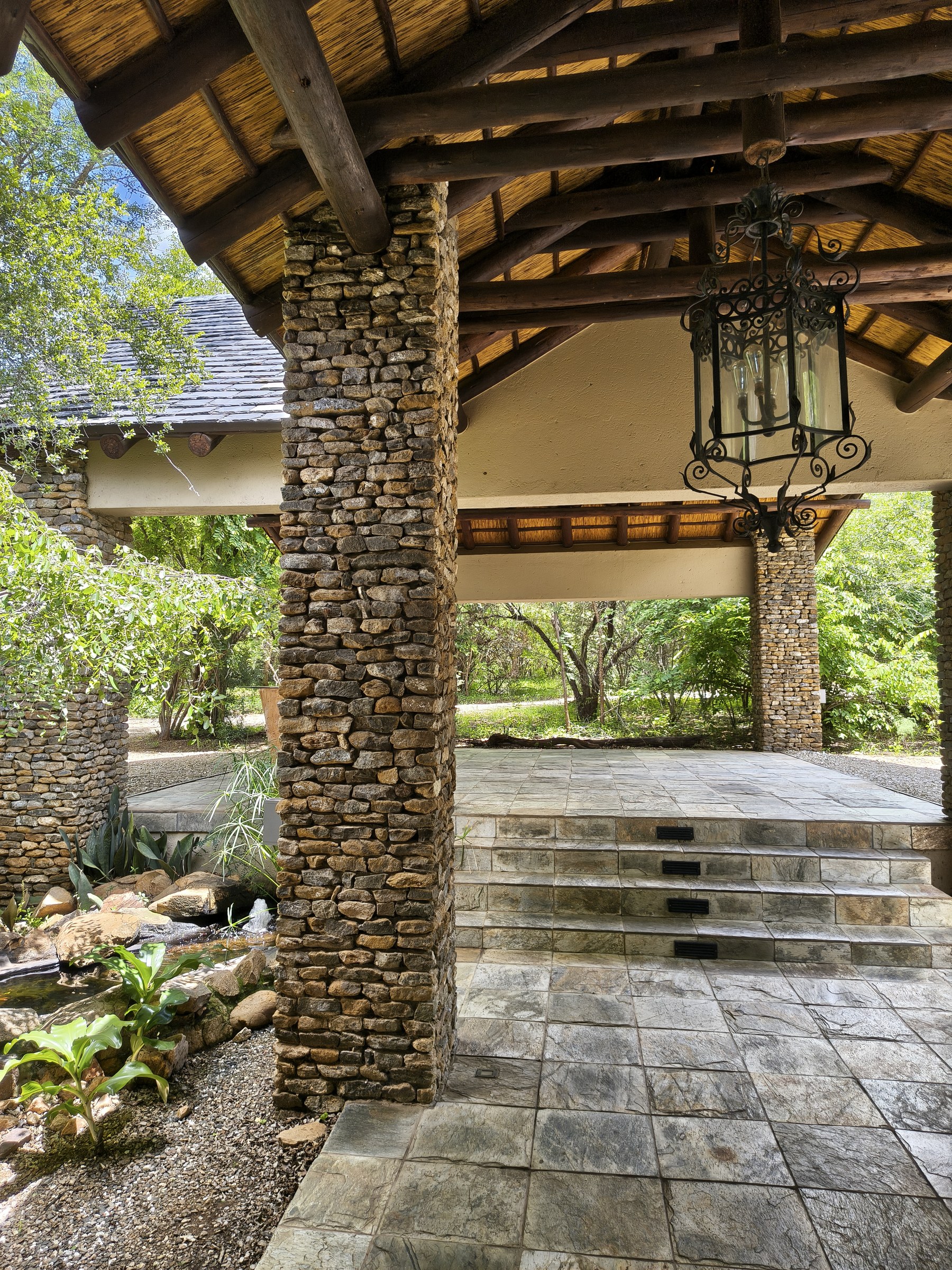 Stone walkway with wrought-iron lantern under the thatched entrance